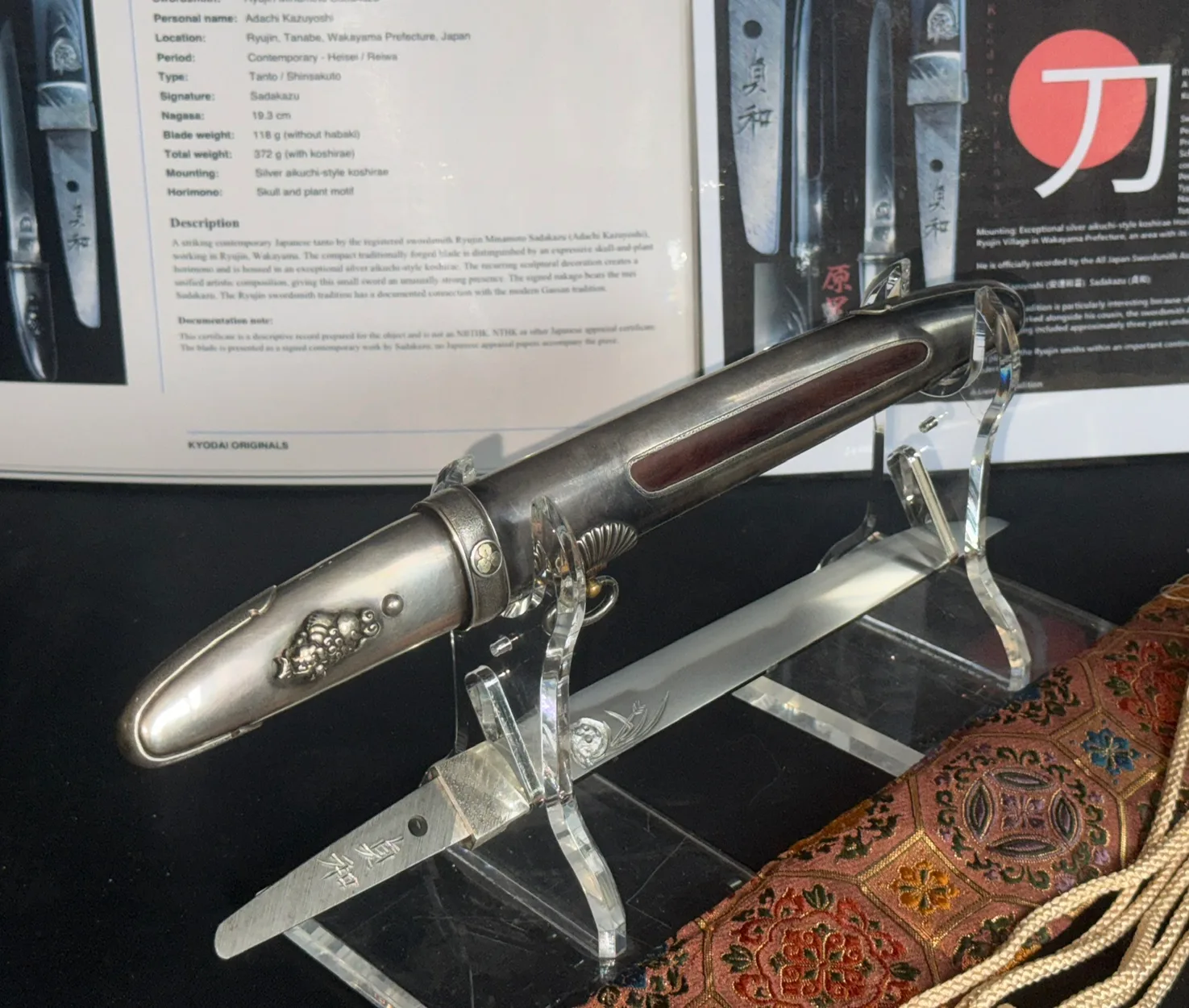 Silver Skull Tantō by Ryūjin Minamoto Sadakazu, a silver-mounted tanto with skull details, displayed on stand