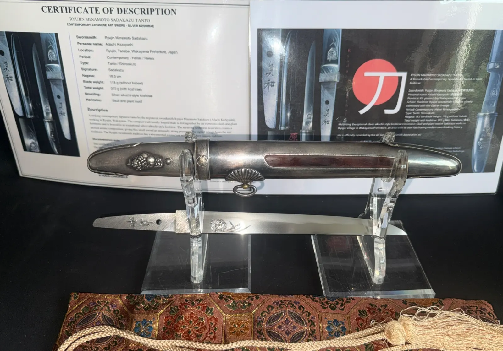 Silver Skull Tantō by Ryūjin Minamoto Sadakazu, blade visible, silver aikuchi koshirae with skull motif on stand