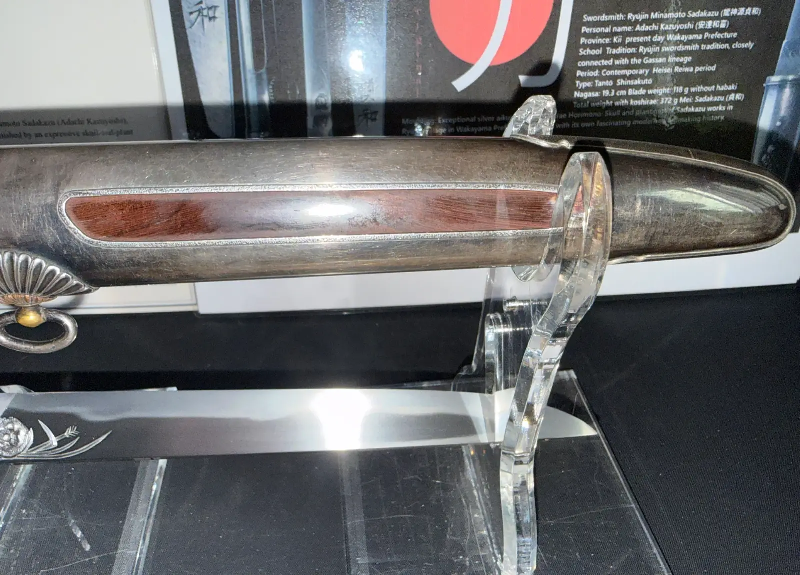 Silver Skull Tantō by Ryūjin Minamoto Sadakazu, partially sheathed, showing silver scabbard with wood inlay and blade.
