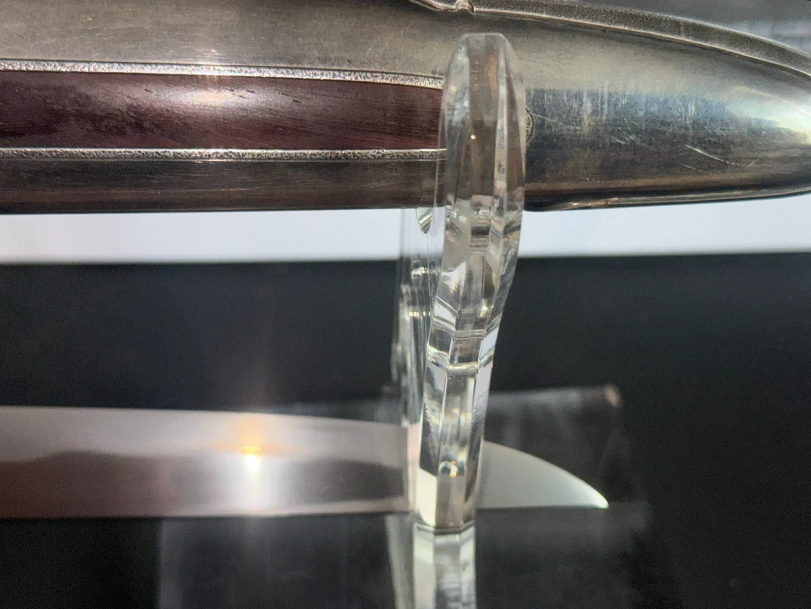 Silver Skull Tanto by Sadakazu, close-up of blade and scabbard in clear stand, wood and silver details visible.