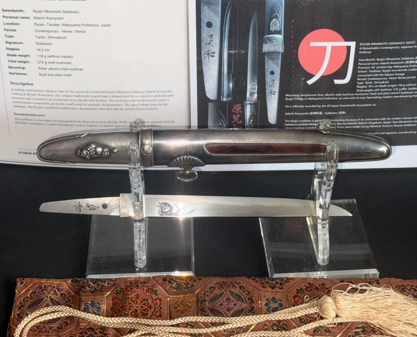 Silver Skull Tantō by Ryūjin Minamoto Sadakazu, silver koshirae with skull motif, blade shown on display stand
