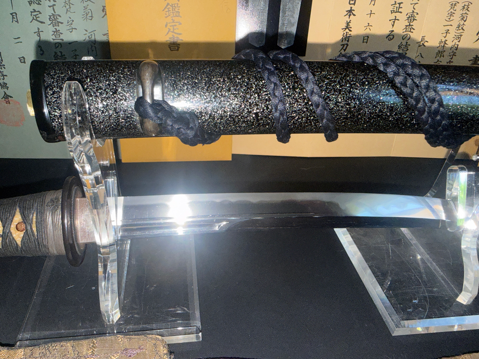 Kawachi no Kami Hironobu Tantō, close-up of polished blade and sparkling black scabbard, on display stands