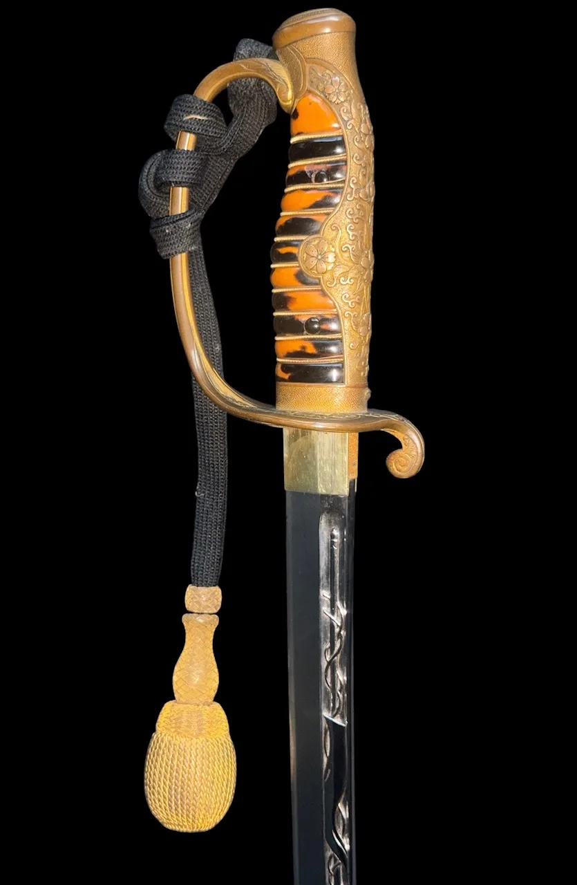 Kyū-Guntō katana, close-up of gold hilt with tortoiseshell grip and visible blade horimono, with black and gold cord.