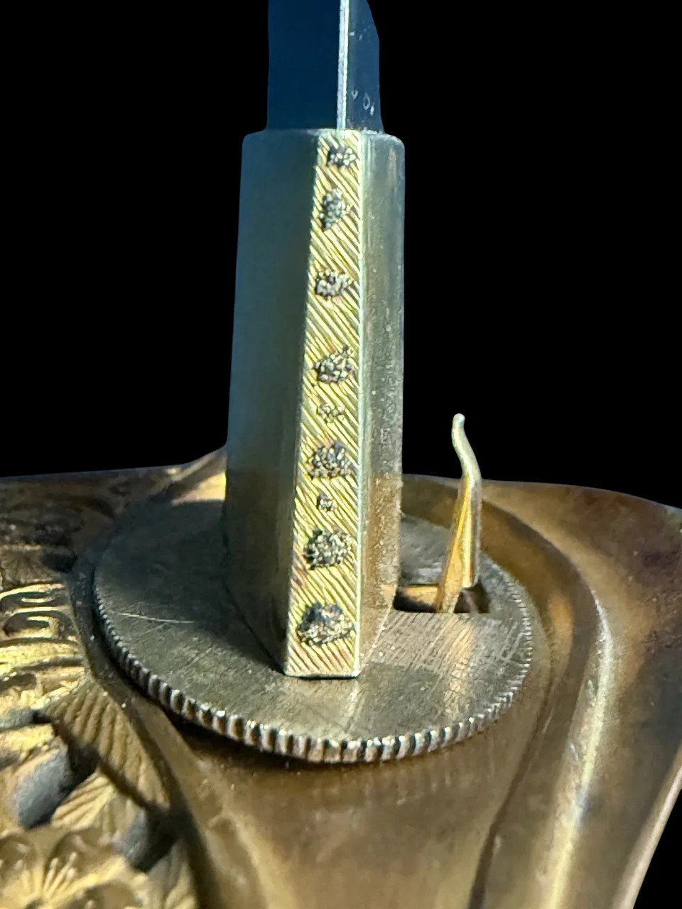 Close-up of a Kyū-Guntō katana's ornate gold hilt release mechanism and Gassan school Nihontō blade base.