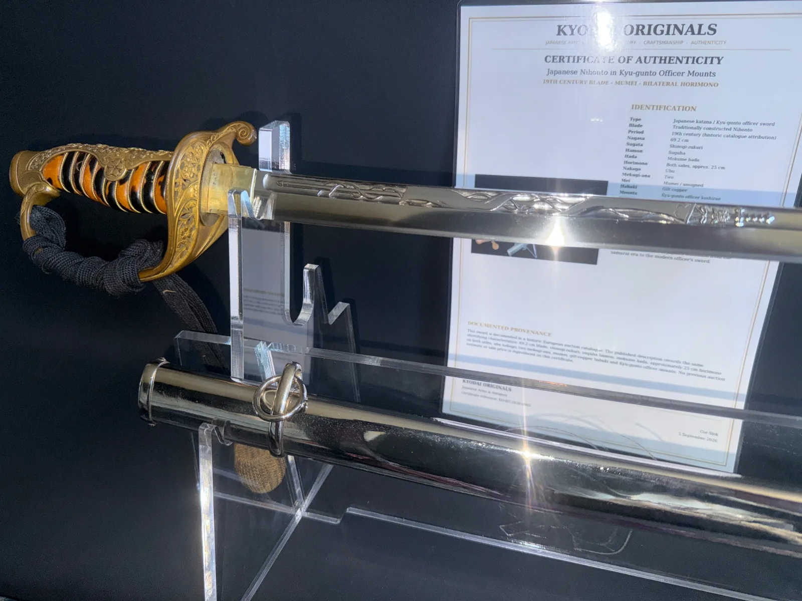Japanese General Officer’s Kyū-Guntō katana on stand, showing ornate golden hilt and detailed horimono blade