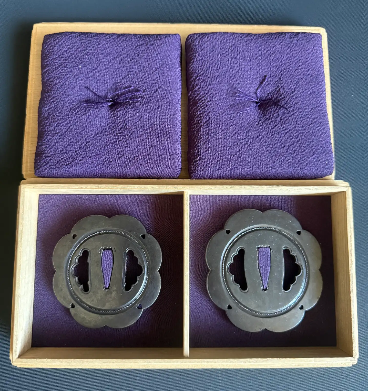 Kamiyoshi Fukanobu Daishō Tsuba Set Tokubetsu Hozon, two dark metal Tsuba in a wooden box with purple silk lining