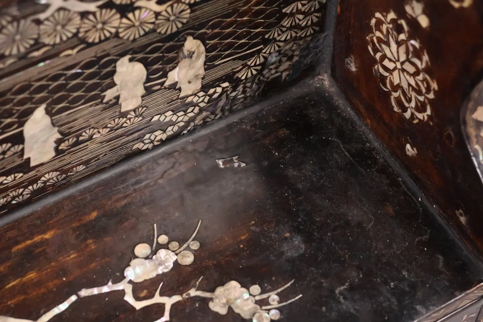 Close-up of intricate raden inlay on an antique Japanese Silver Katana Kake accessory, featuring figures and floral motifs