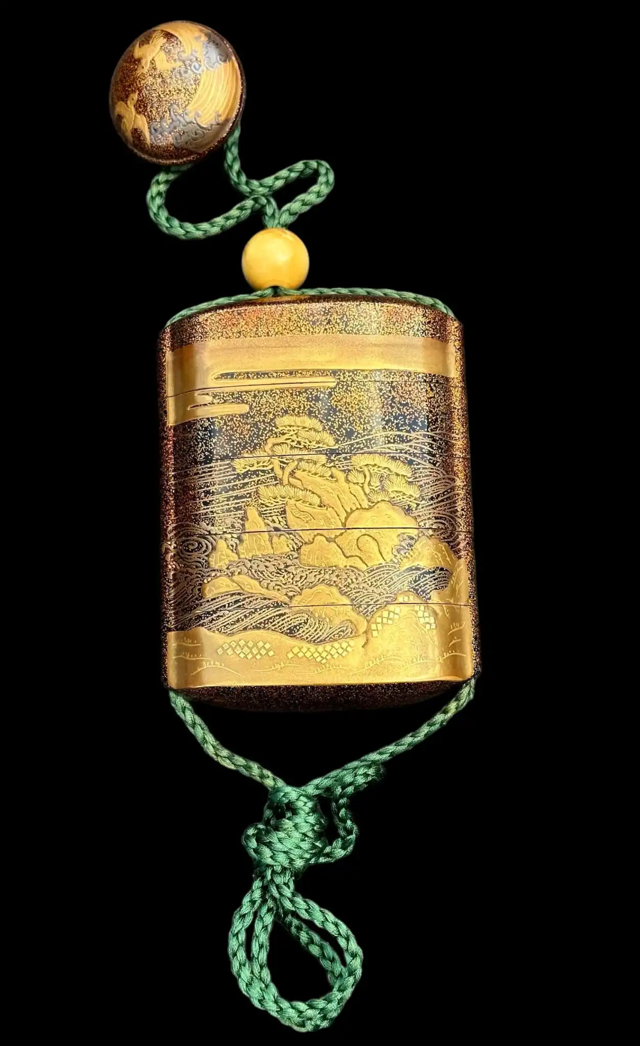 Close-up of an Antique Inro 1840 Makie accessory with intricate gold lacquer painting on a dark background