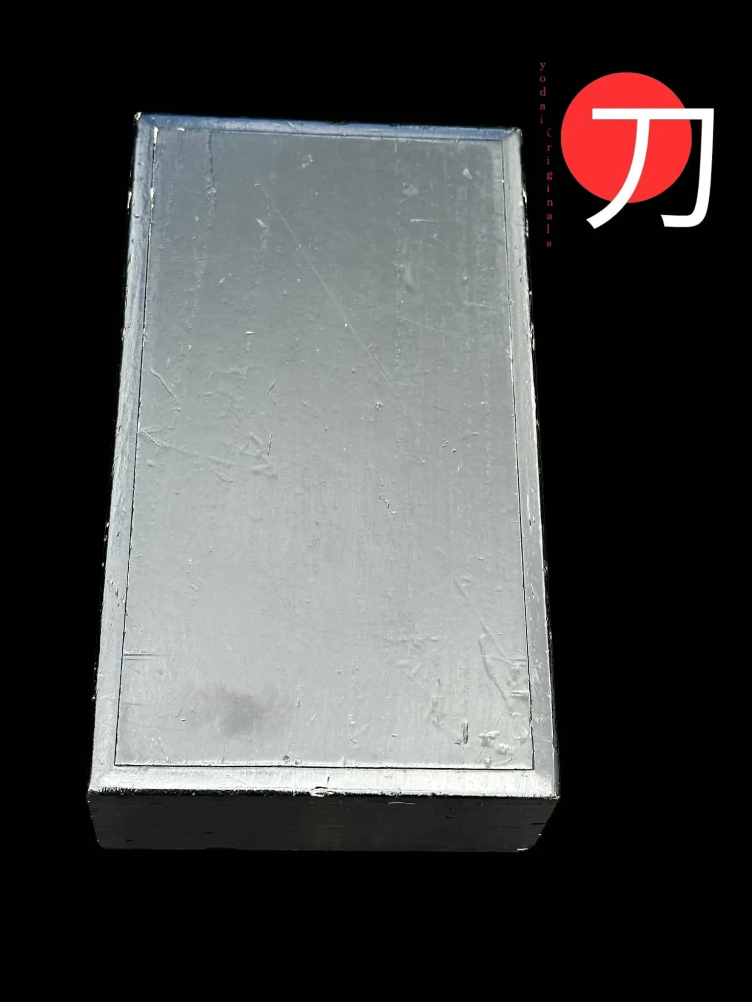 Top-down view of a rectangular, shiny, silver-gray box, an Antique Inro 1840 Makie accessory from Kyodai Originals