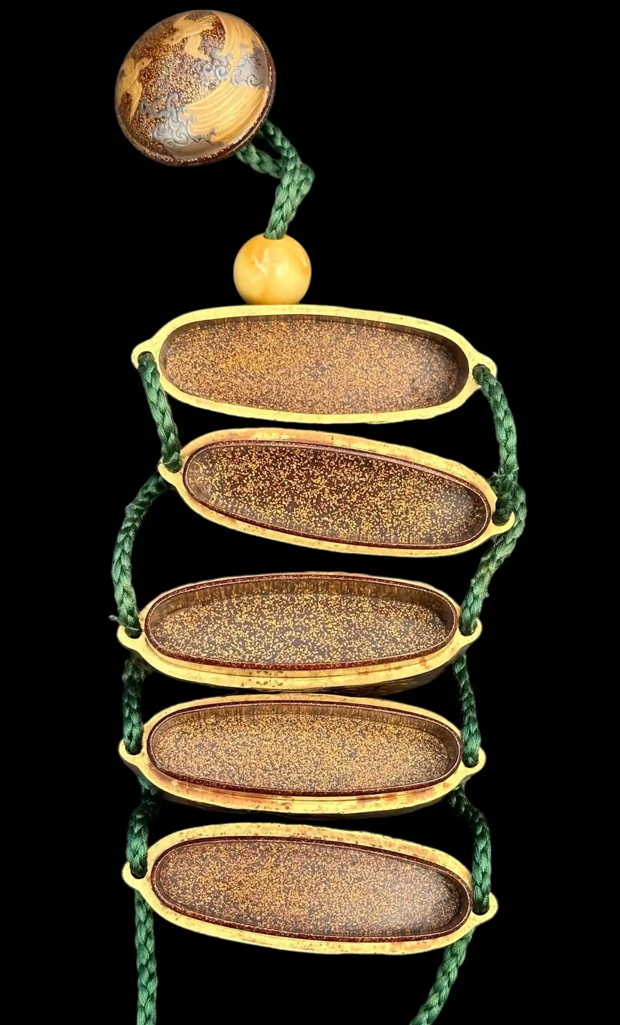 Close-up view of an open Antique Inro 1840 Makie accessory showing its internal compartments and cord.