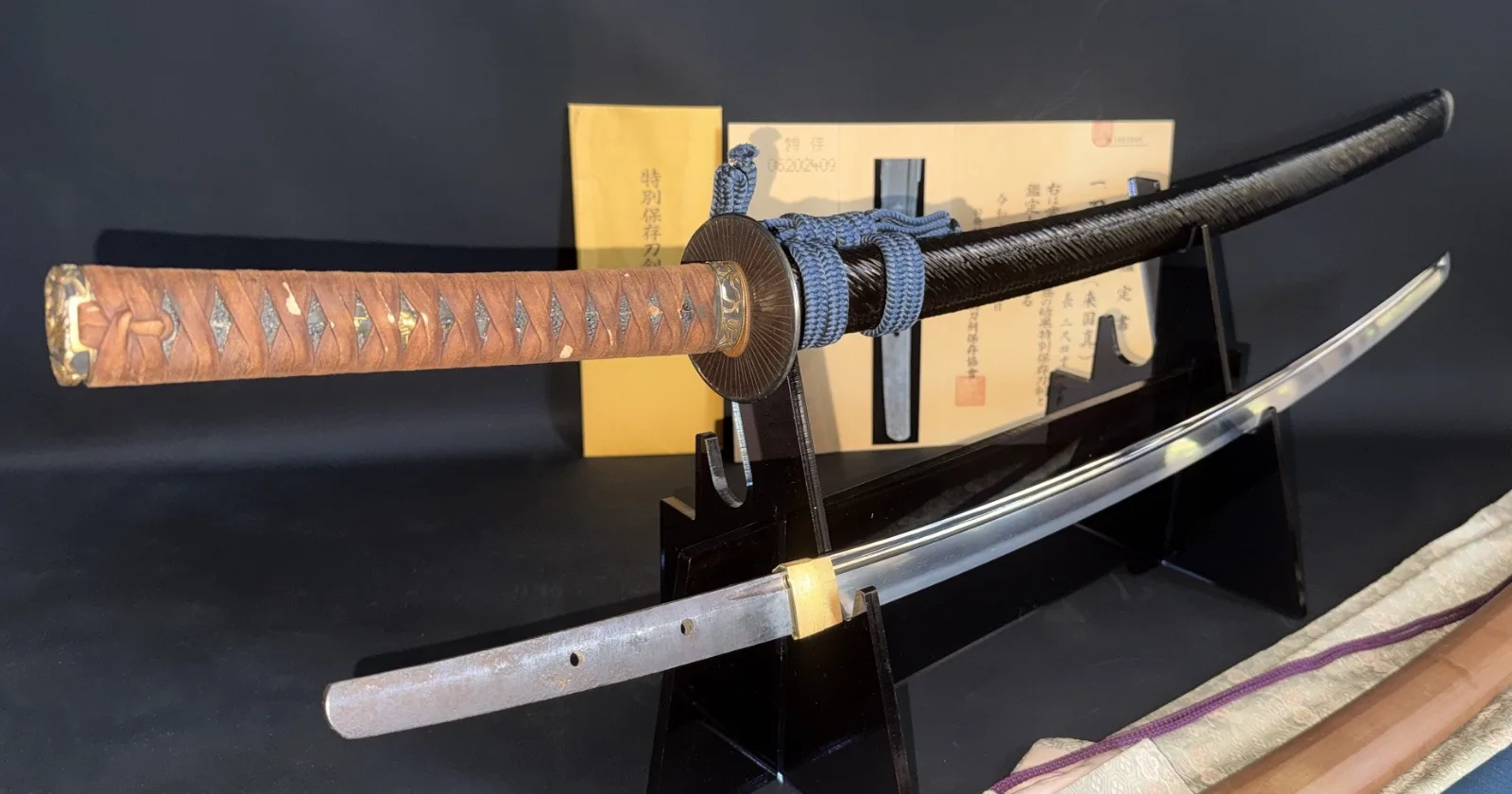 Kamakura Katana Rai Kunizane Tokubetsu Hozon, a Japanese katana with brown tsuka displayed on a black stand