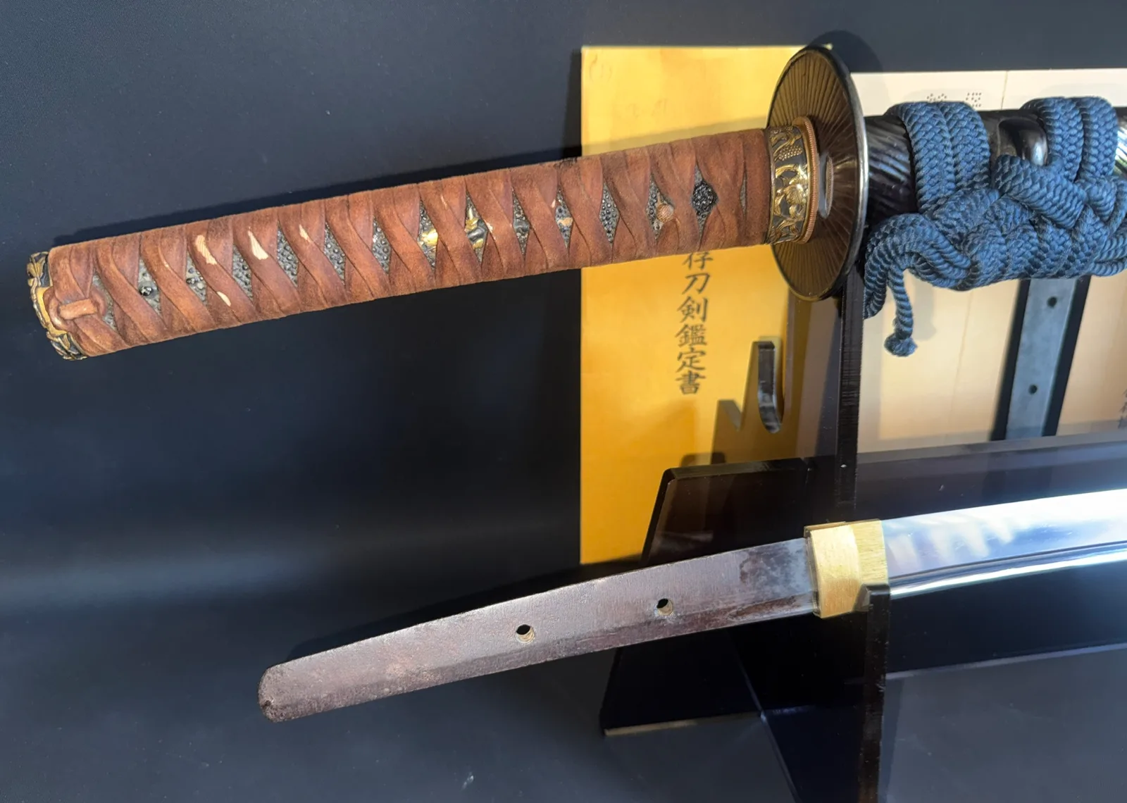 Kamakura Katana Rai Kunizane Tokubetsu Hozon, katana with visible tang and brown wrapped tsuka against a dark background