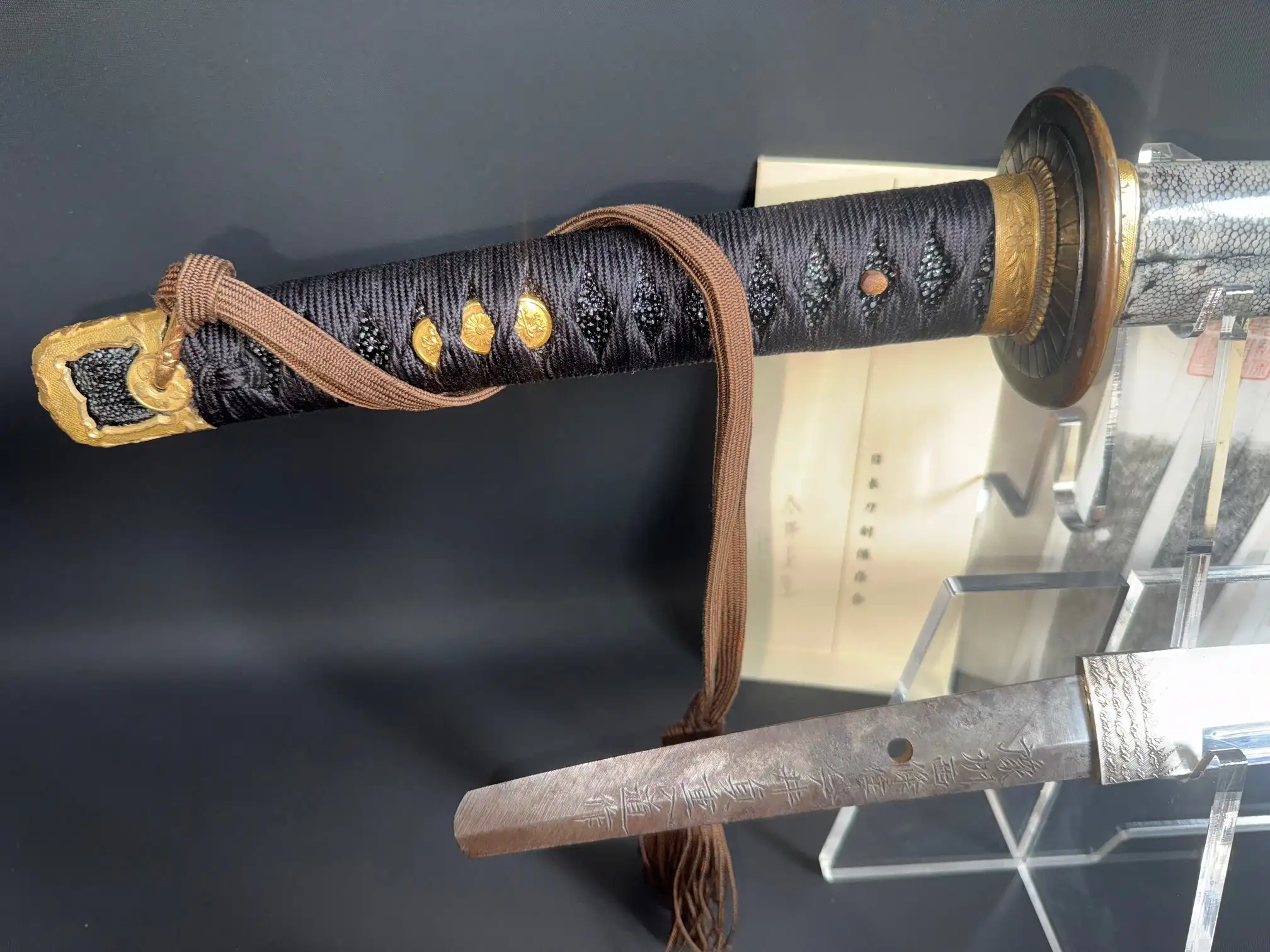 Naval Commissioned Gendaitō katana by Sadashige Gassan, close-up of dark hilt with golden accents and visible tang