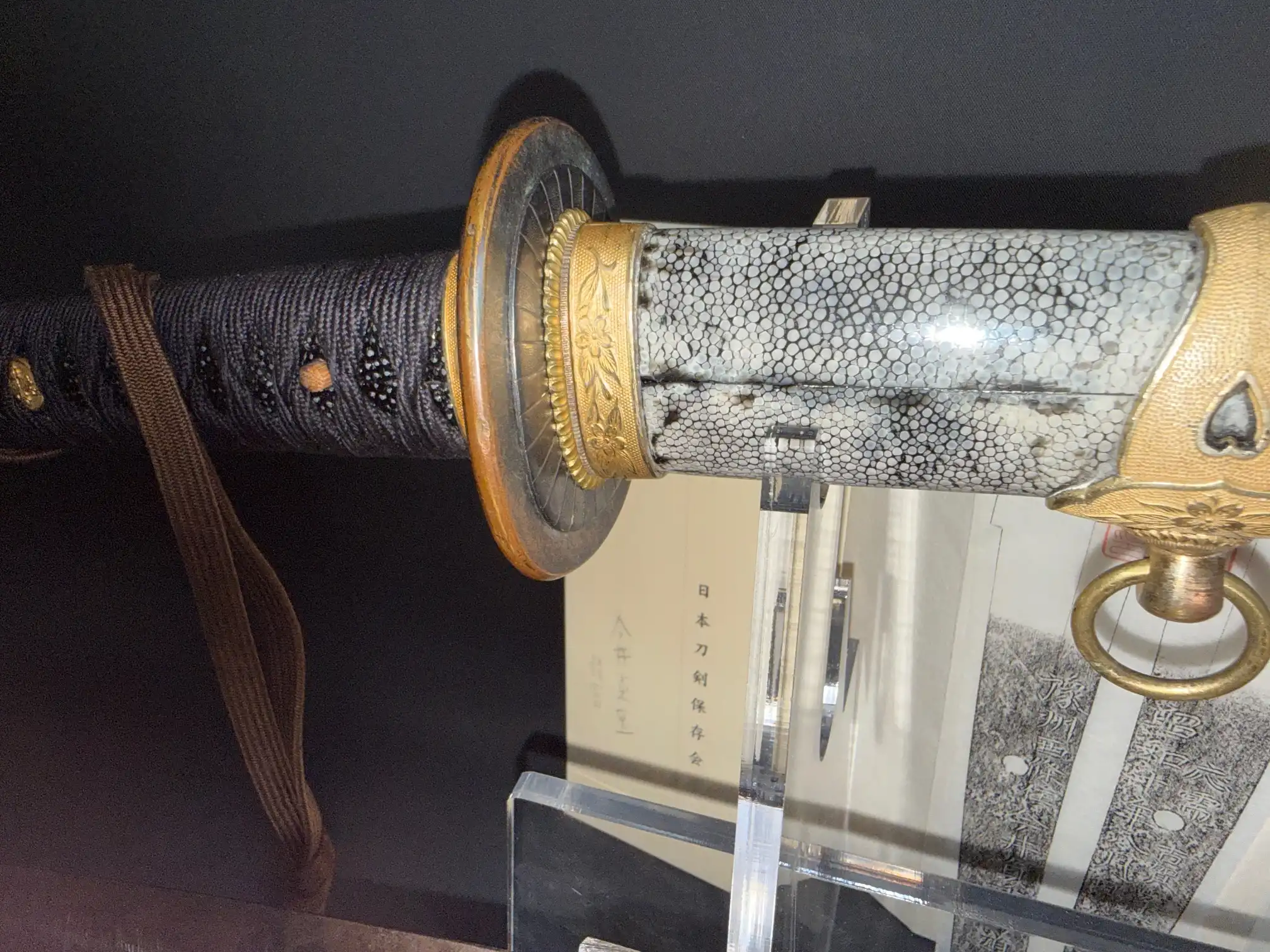 Close-up of a Naval Commissioned Gendaitō katana by Sadashige Gassan, showing the black tsuka and ray skin saya.