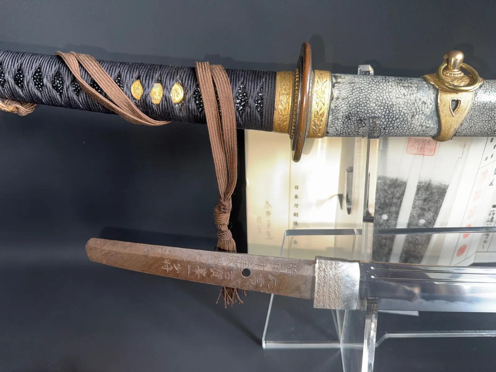 Naval Commissioned Gendaitō katana by Sadashige Gassan, close-up of handle and engraved tang on display.