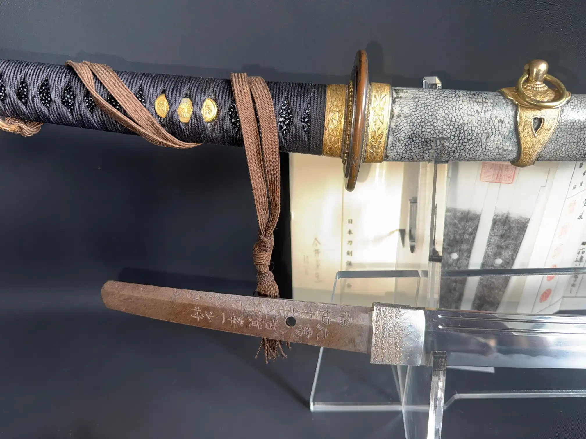 Naval Commissioned Gendaitō katana by Sadashige Gassan, close-up of handle and engraved tang on display.