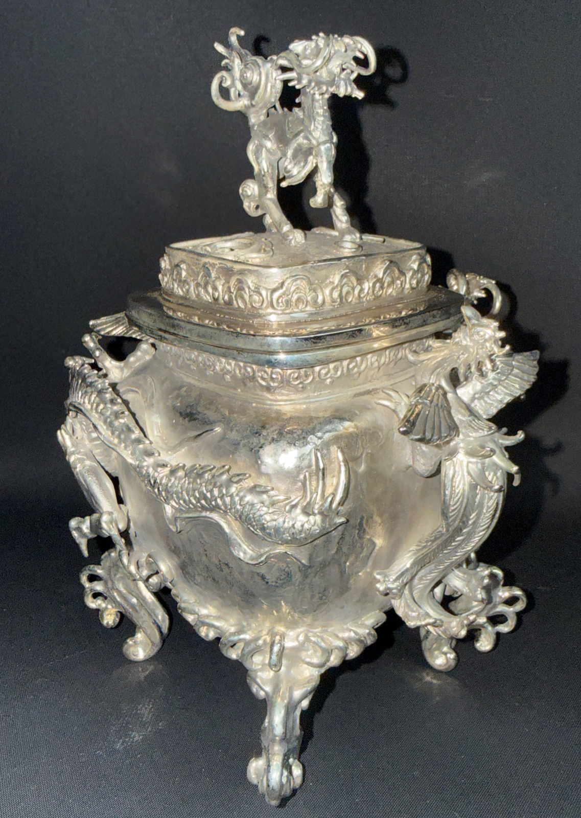 Silver Takaoka Bronze Kōro ACCESSORIES by Suga Tsukiyoshi with ornate dragon-like details and lid figure, viewed from an angle