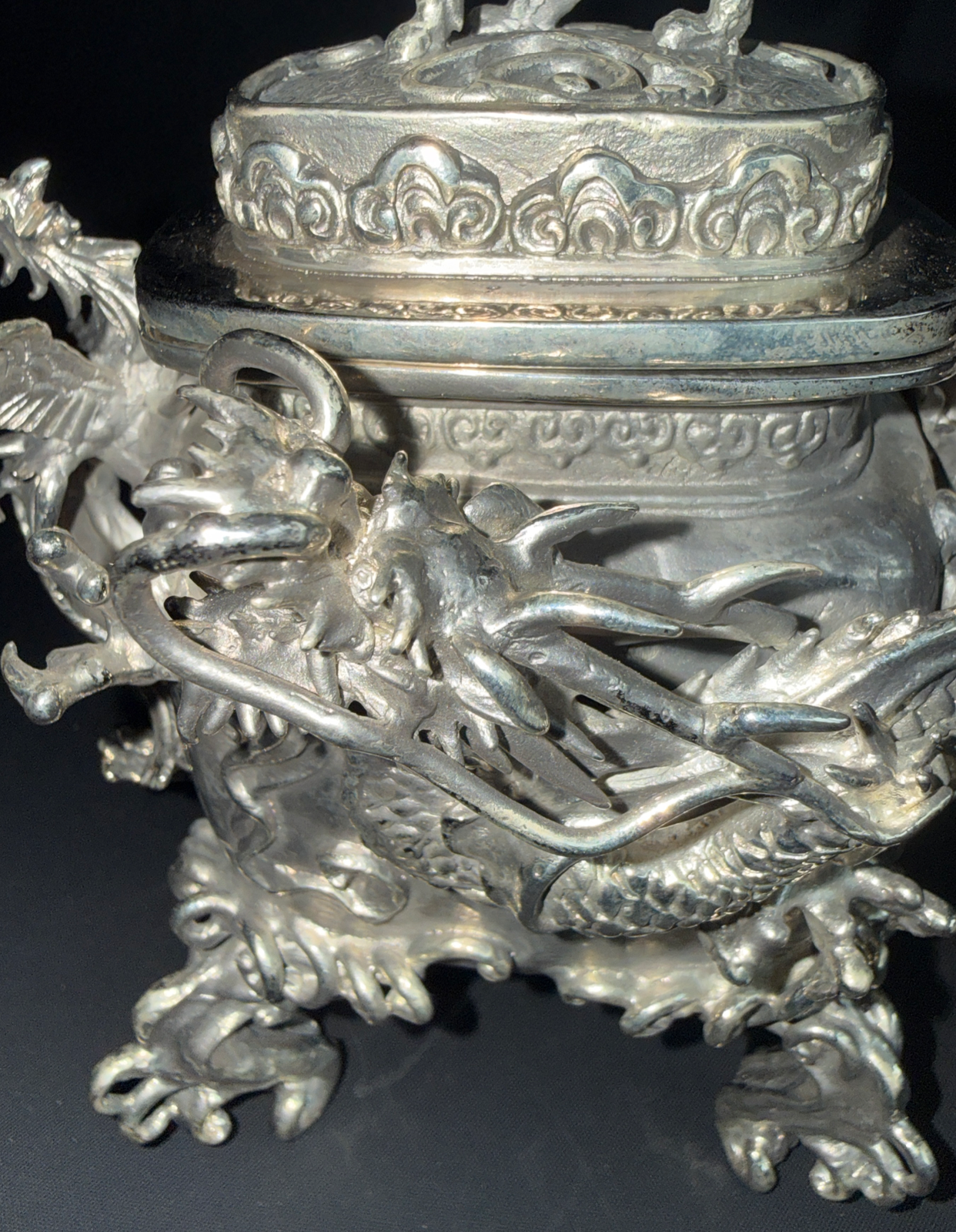 Close-up of a silver Takaoka Bronze Kōro ACCESSORIES, adorned with intricate dragon and cloud patterns