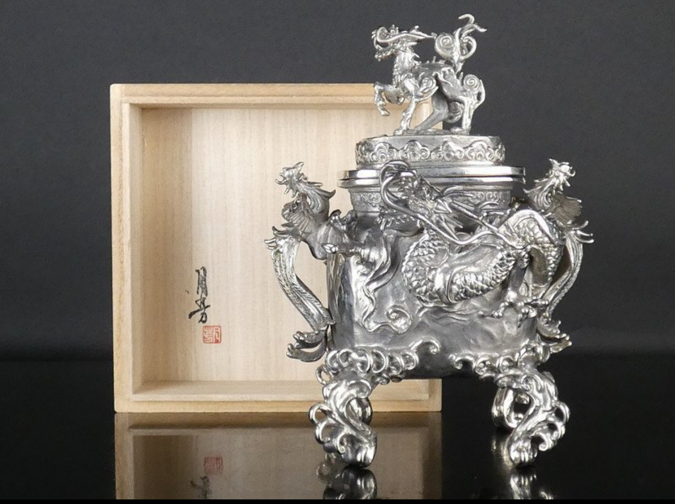 Side view Takaoka Bronze Kōro with intricate dragon detailing & lid finial, set against wooden box. Kyodai Originals ACCESSORIES.