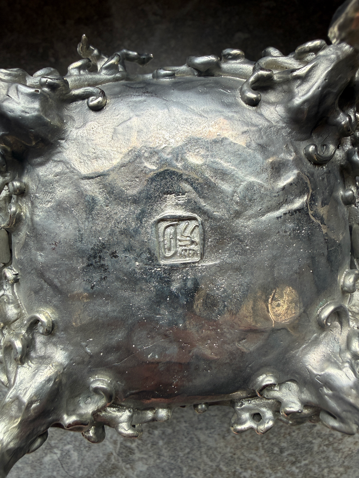 Top-down view of the textured silver Takaoka Bronze Kōro ACCESSORY, showing the engraved artist's mark in detail.