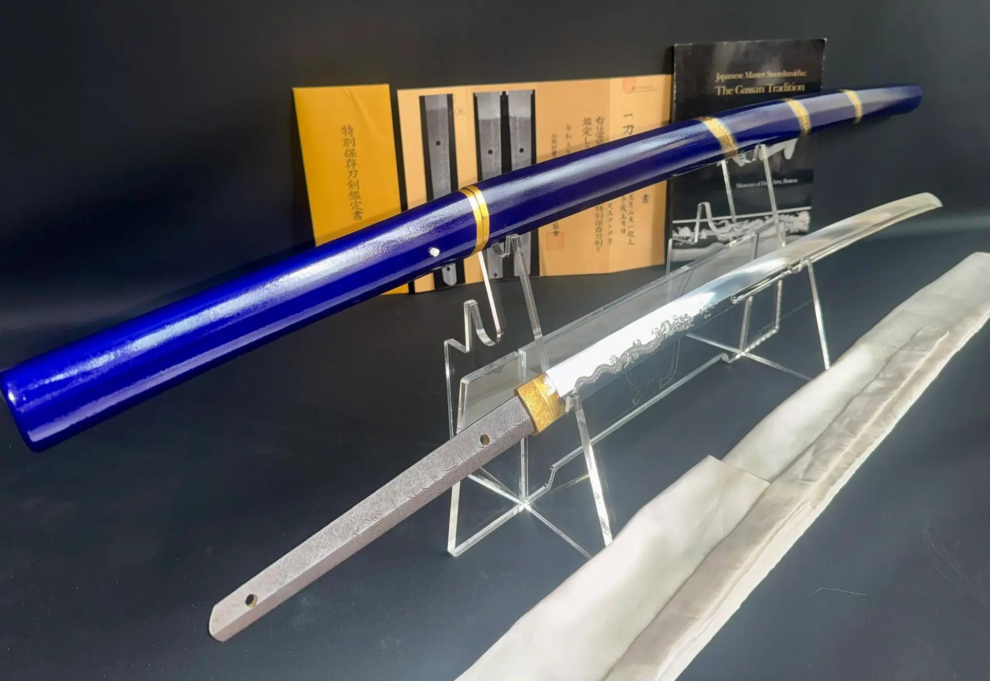 Blue scabbard, blade, and documents on display for the Japanese Masterpice Gassan Sadakazu katana.