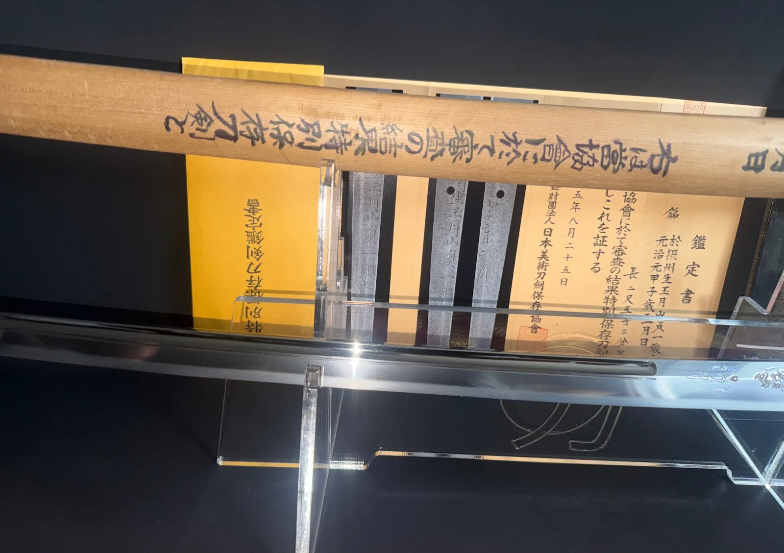 Gassan Sadakazu katana blade with engraved documentation and wooden saya in display case