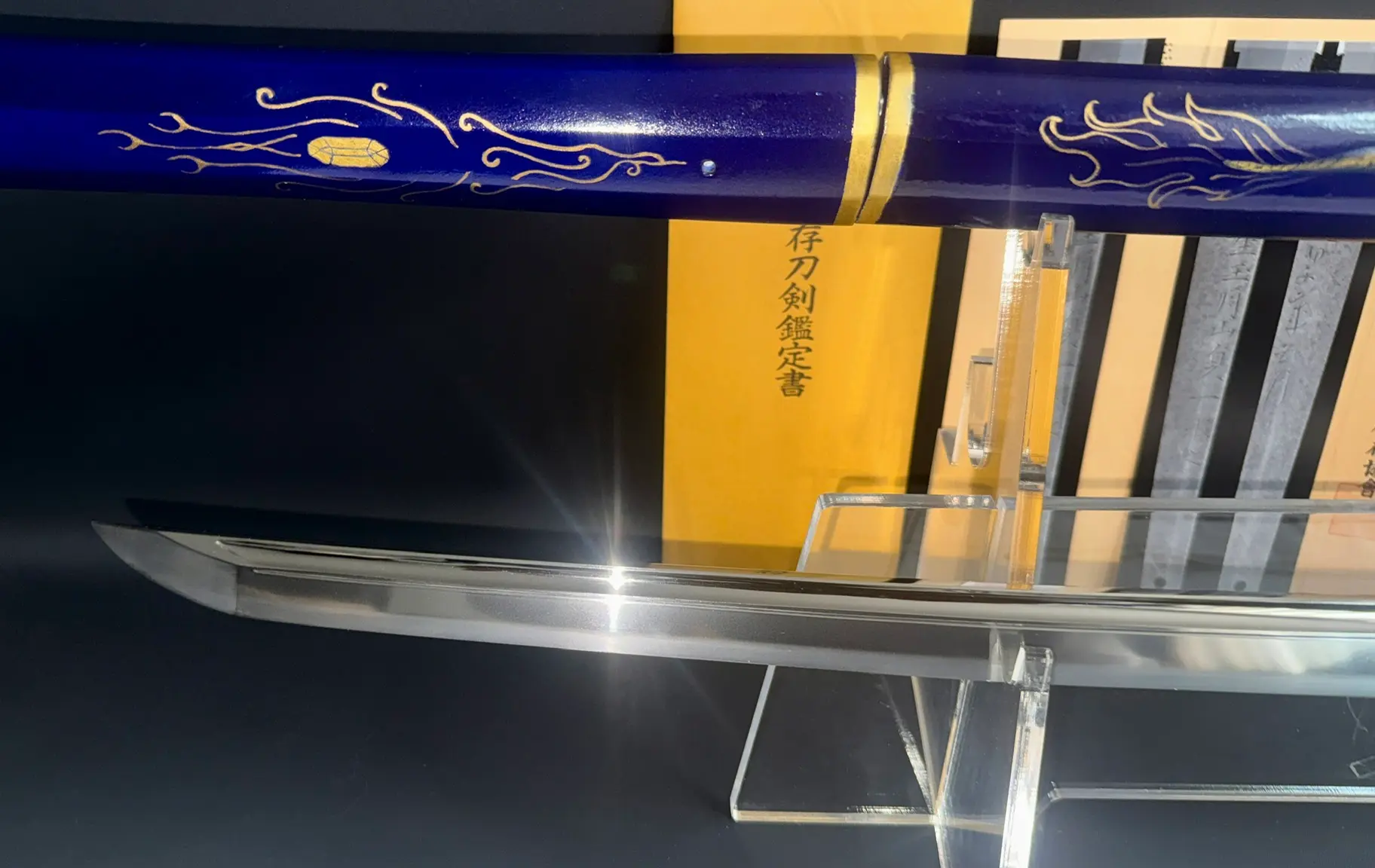 Gassan Sadakazu NBTHK Tokubetsu Hozon katana blade close-up, tip reflects light, blue scabbard behind.