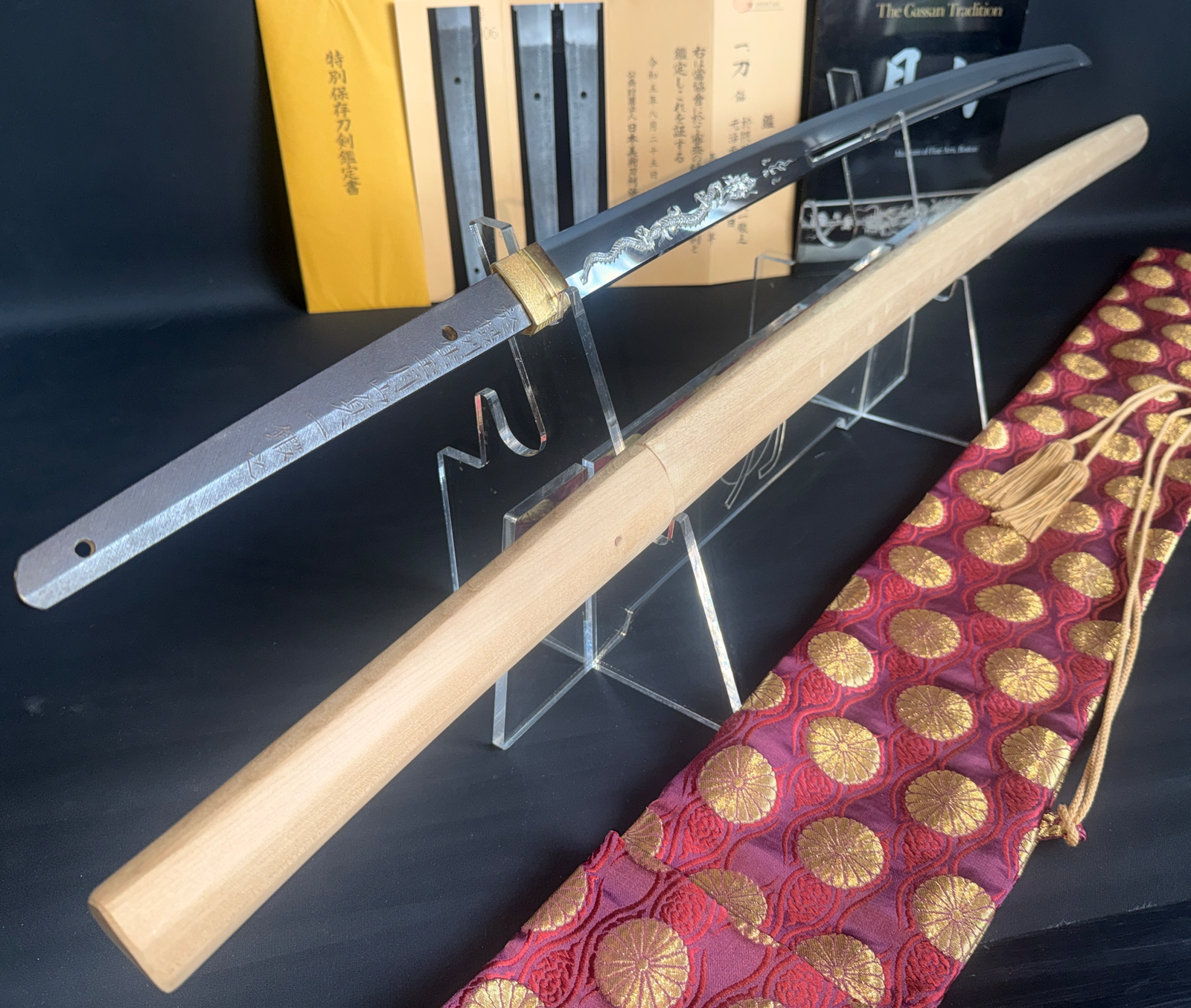 Japanese Masterpiece Katana by Gassan Sadakazu on stand with wooden scabbard, dragon engraving, and silk bag