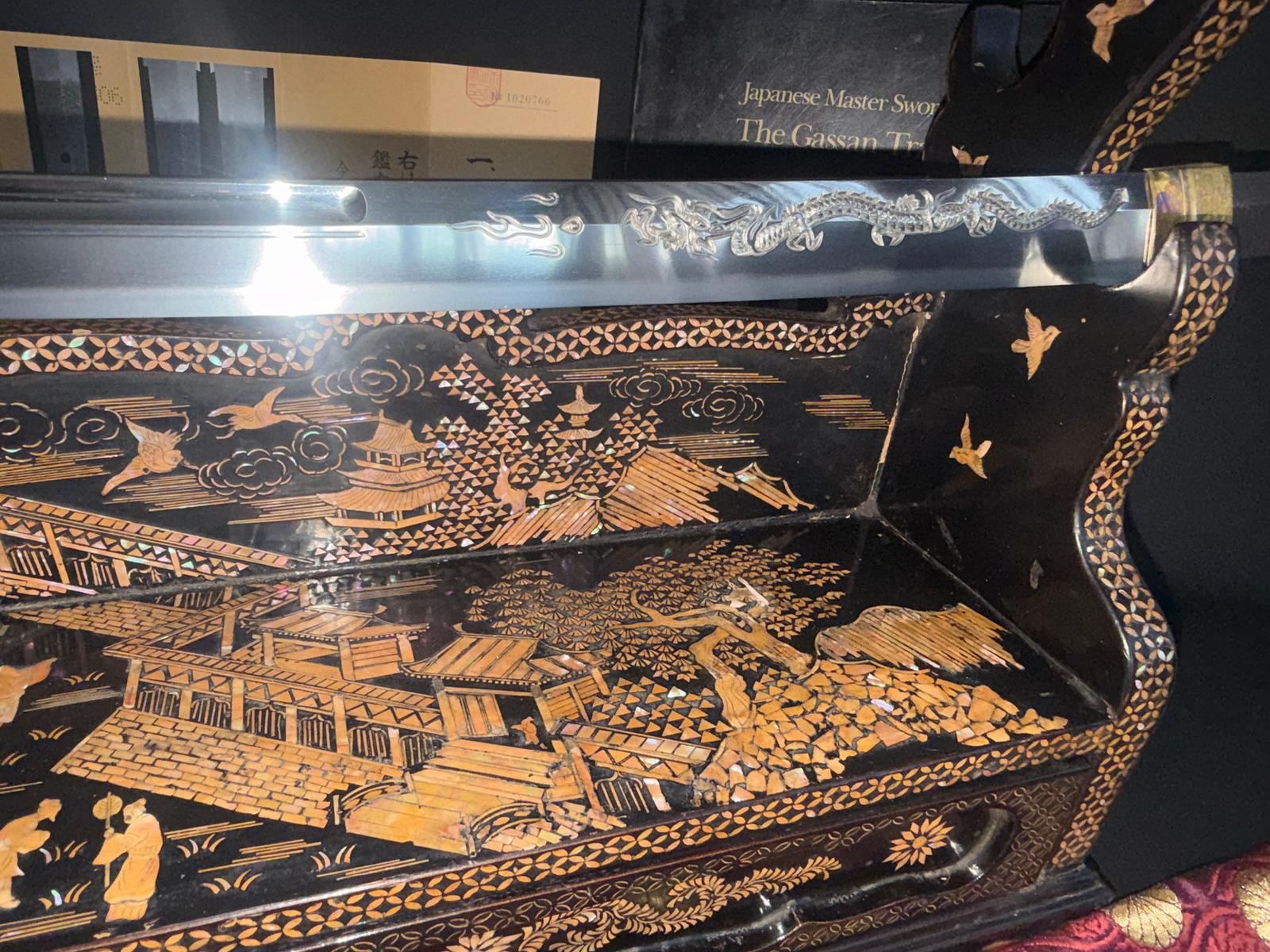 Japanese Masterpiece Katana by Gassan Sadakazu with dragon carving, resting on a mother-of-pearl inlaid katana stand