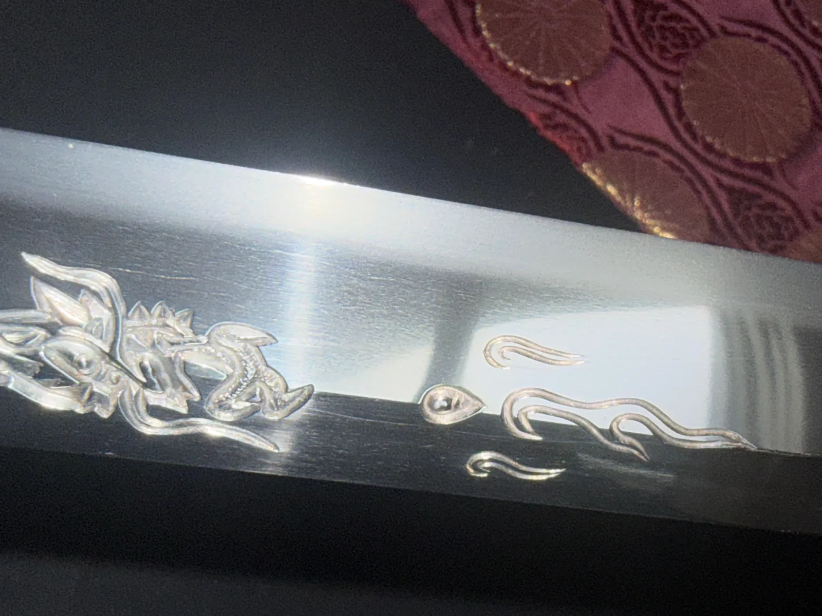Close-up of a Gassan Sadakazu katana blade with intricate silver dragon horimono and polished steel surface