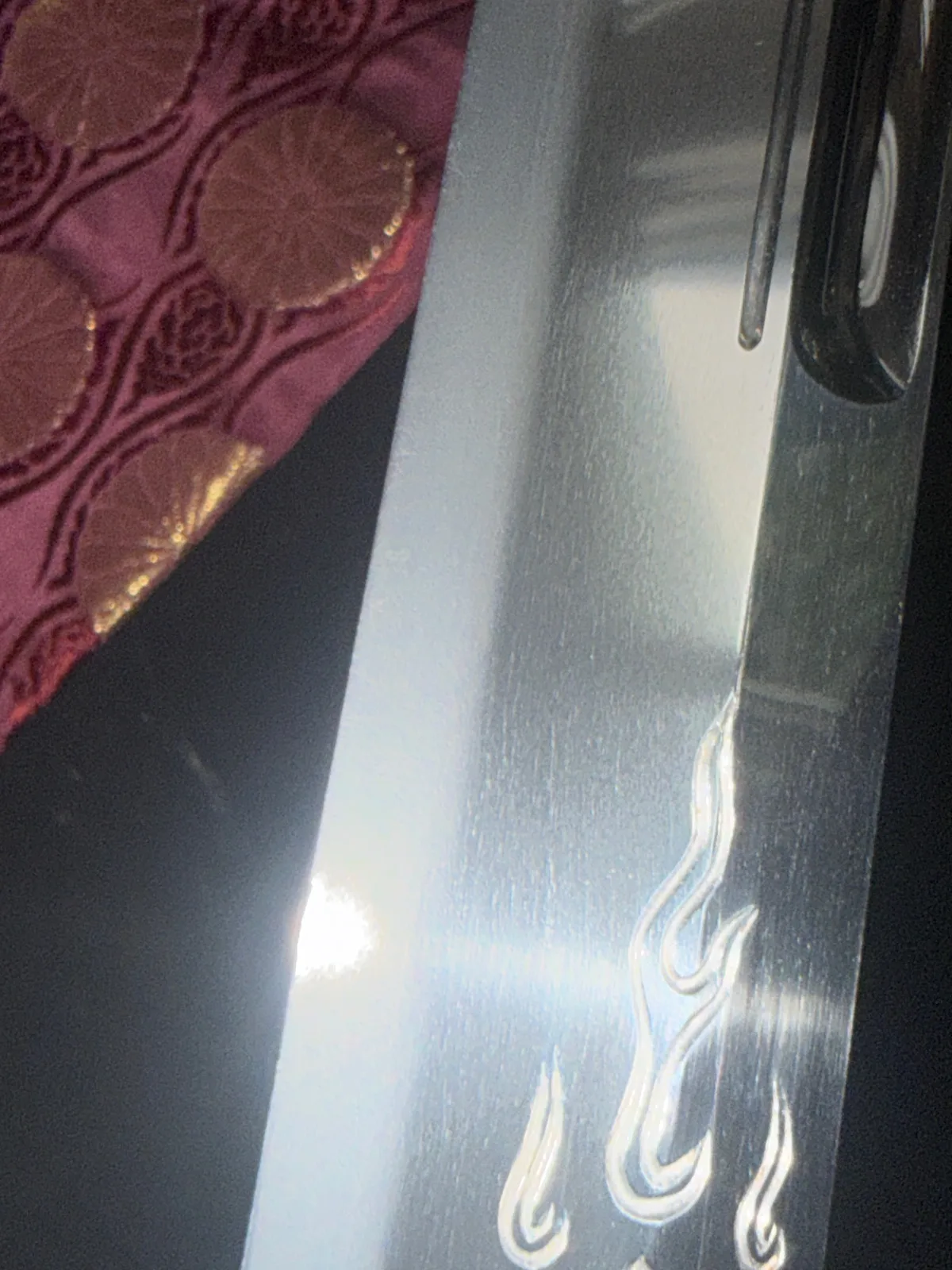 Close-up of Gassan Sadakazu Japanese Masterpiece Katana blade with engraved horimono flame motifs, light reflections