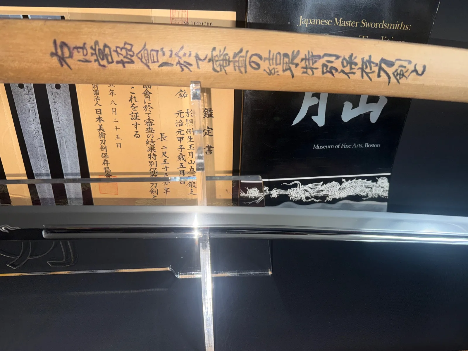 Close-up of a Japanese Masterpiece Katana by Gassan Sadakazu with wood saya and documentation, reflecting blade
