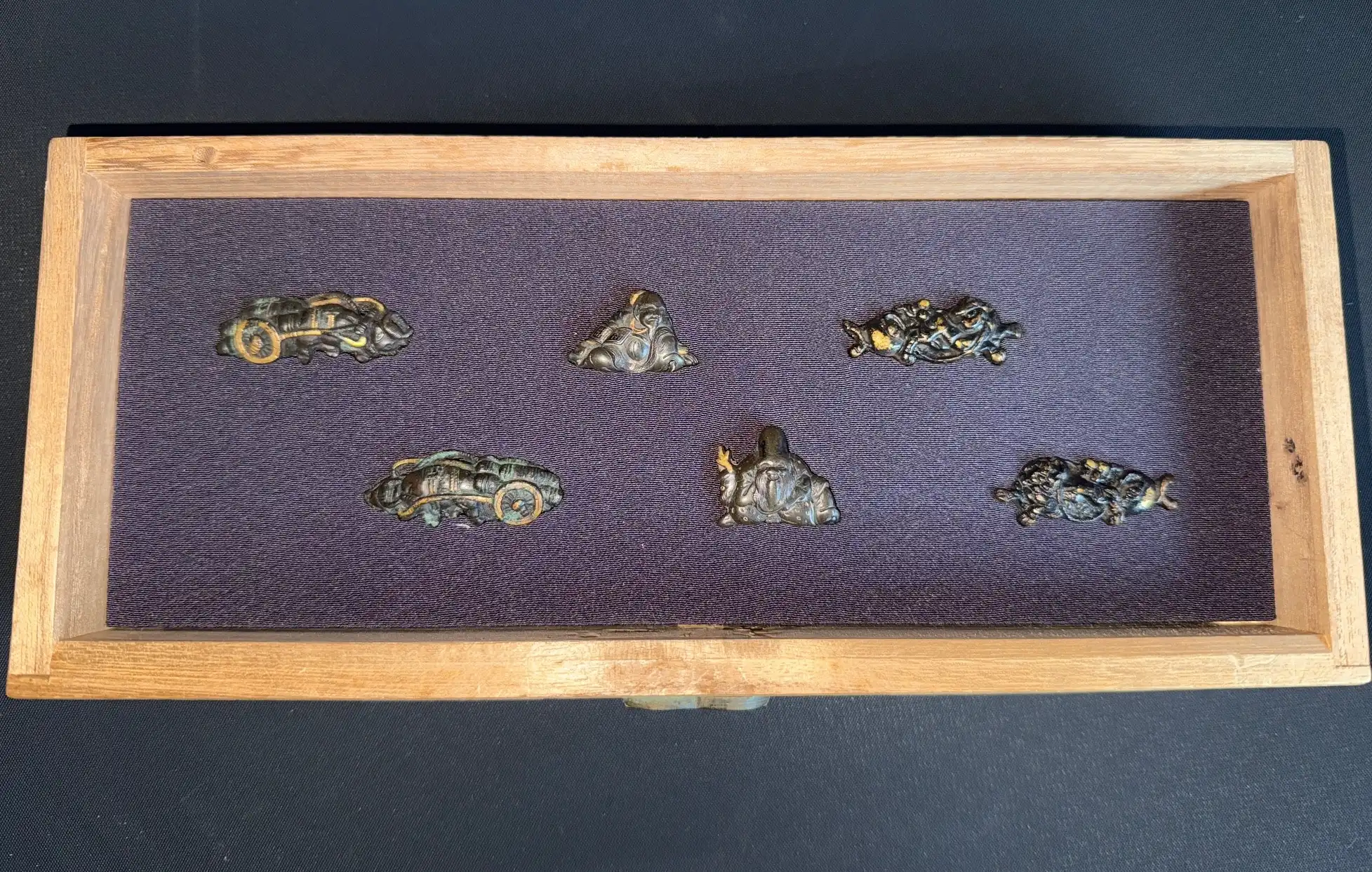 Overhead view of Edo period Menuki 9 pairs (Accessories) in a Kiri box, dark purple fabric lining.