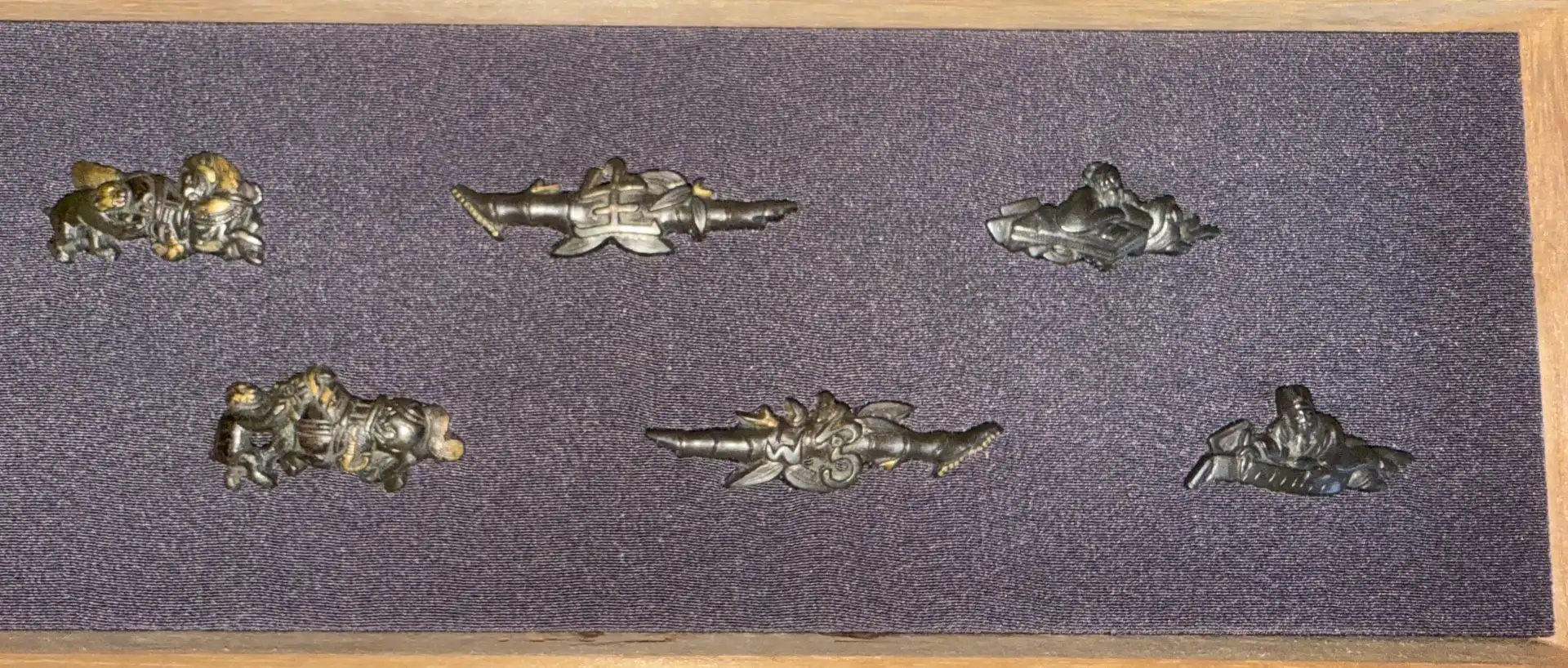 Overhead view of Edo period Menuki 9 pairs hilt Accessories in kiri box, dark background, varying designs