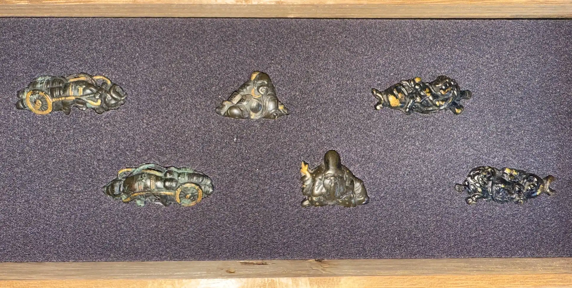Top-down view of six dark Edo period Samurai Sword Menuki accessories, three on top, three on bottom