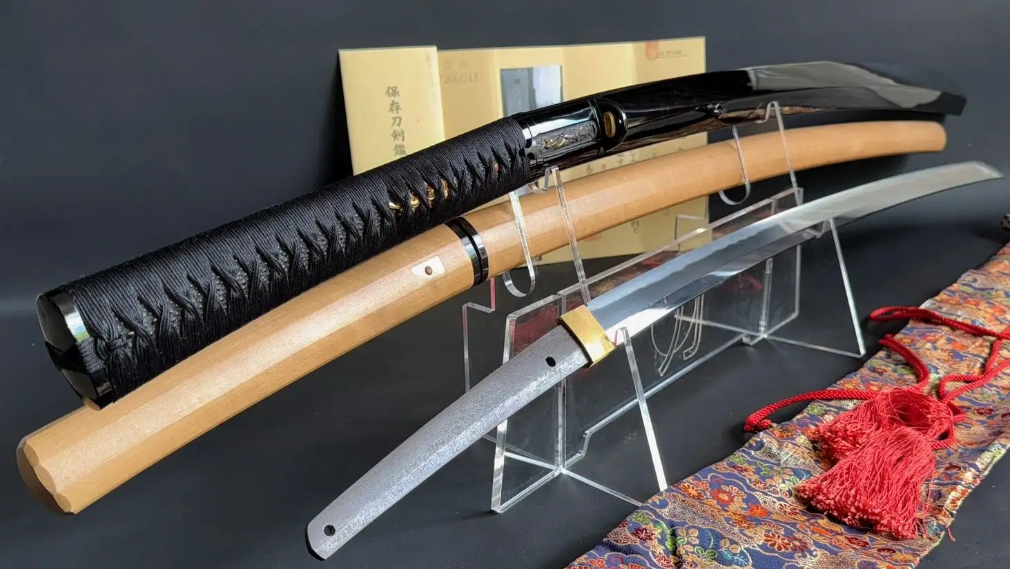 Jinja Hōnō Tachi Naganobu Katana blade, koshirae and shirasaya next to luxurious textile sword bag