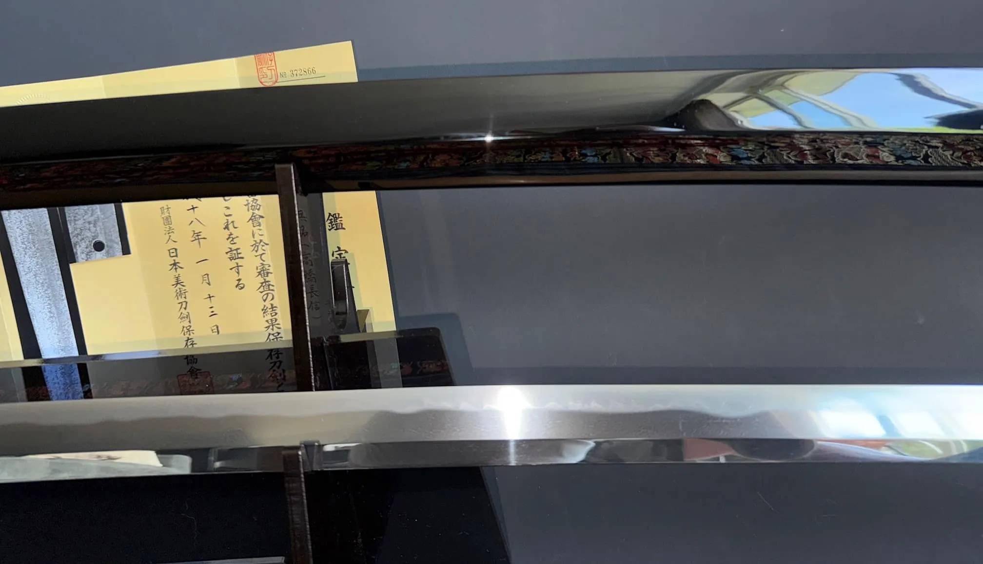 Close-up of Jinja Hōnō Tachi Naganobu Katana blade and ornate saya, with NBTHK Hozon paper