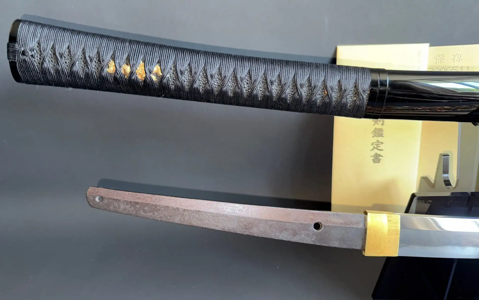Jinja Hōnō Tachi Naganobu Katana, tang and black tsuka with gold details viewed from above.