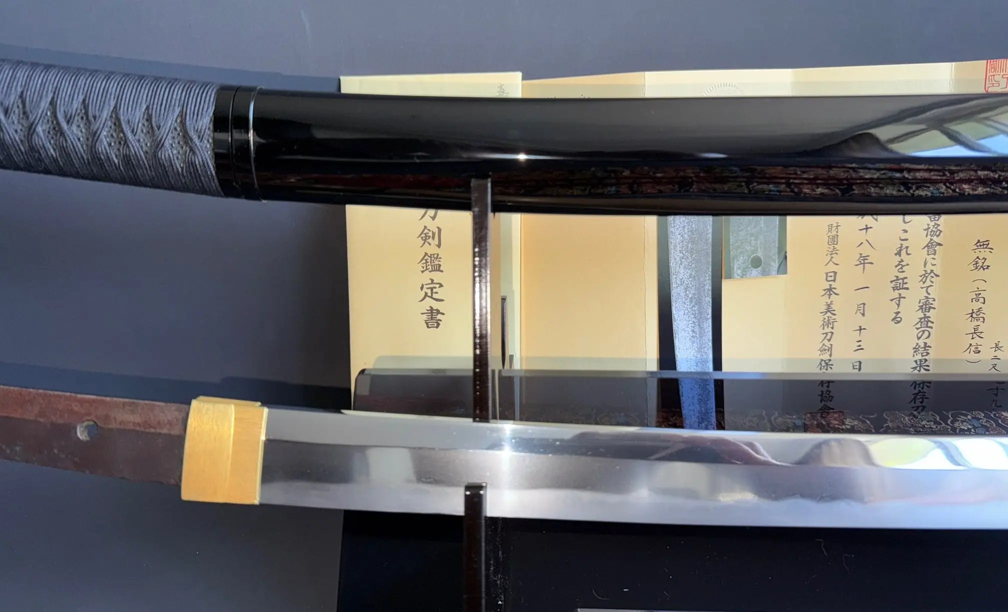 Close-up of a Jinja Hōnō Tachi Naganobu Katana blade and handle, with certificate visible behind