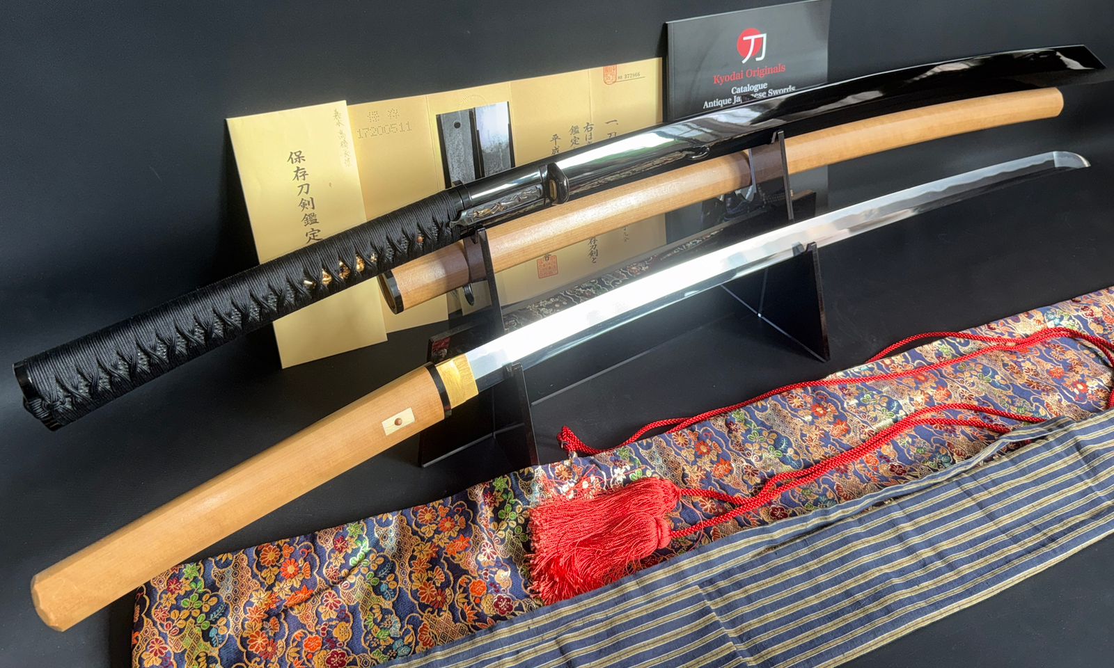 Jinja Hōnō Tachi Naganobu Katana with shimmering blade, black scabbard, and silk sword bag display.