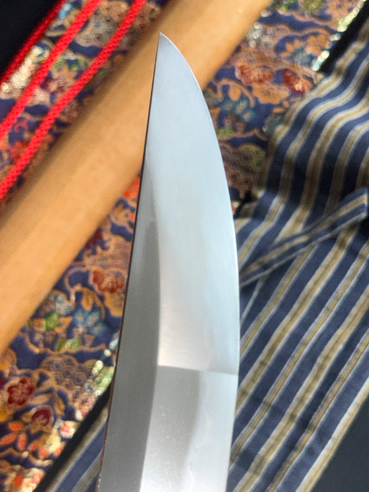 Close up of Jinja Hōnō Tachi Naganobu katana blade tip, showing sharp hamon and polished steel.