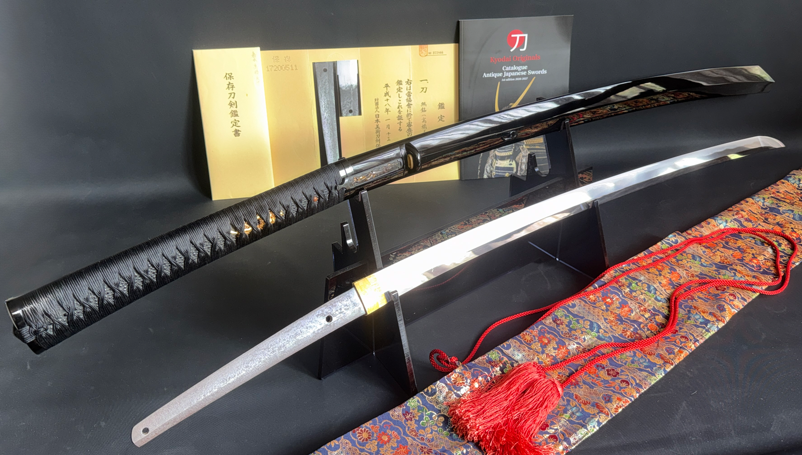 Jinja Hōnō Tachi Naganobu Katana with glossy black saya, blade, and documentation on display