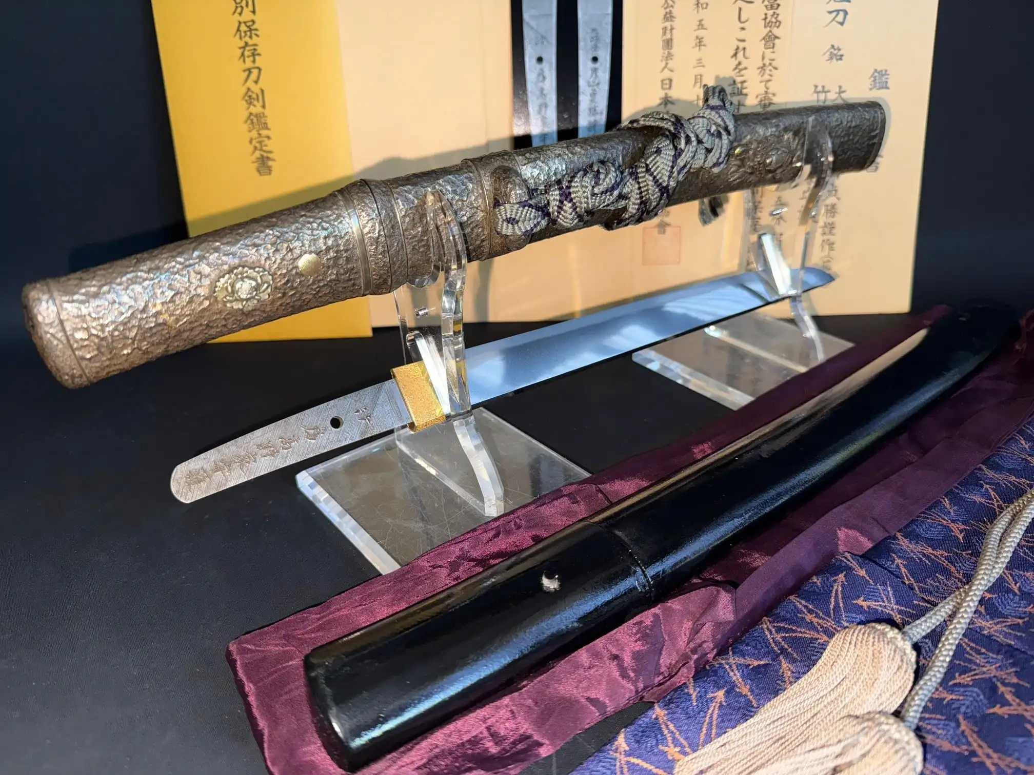 Tanto Gassan Sadakatsu: intricate hammered metal hilt and exposed blade, with black saya and certificate.