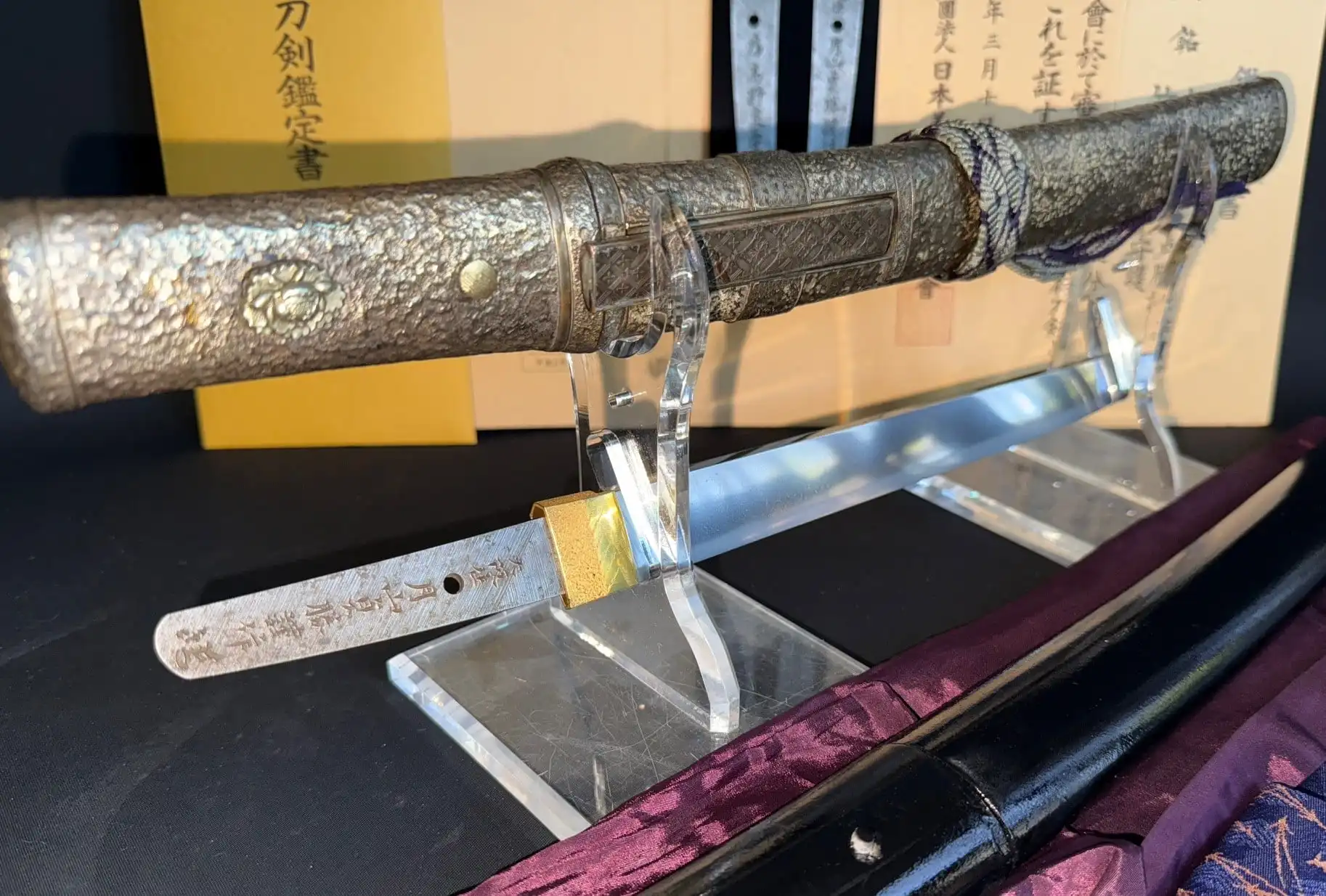 Close-up of a silver-hilted Tanto Gassan Sadakatsu on display by Kyodai Originals with visible blade inscription