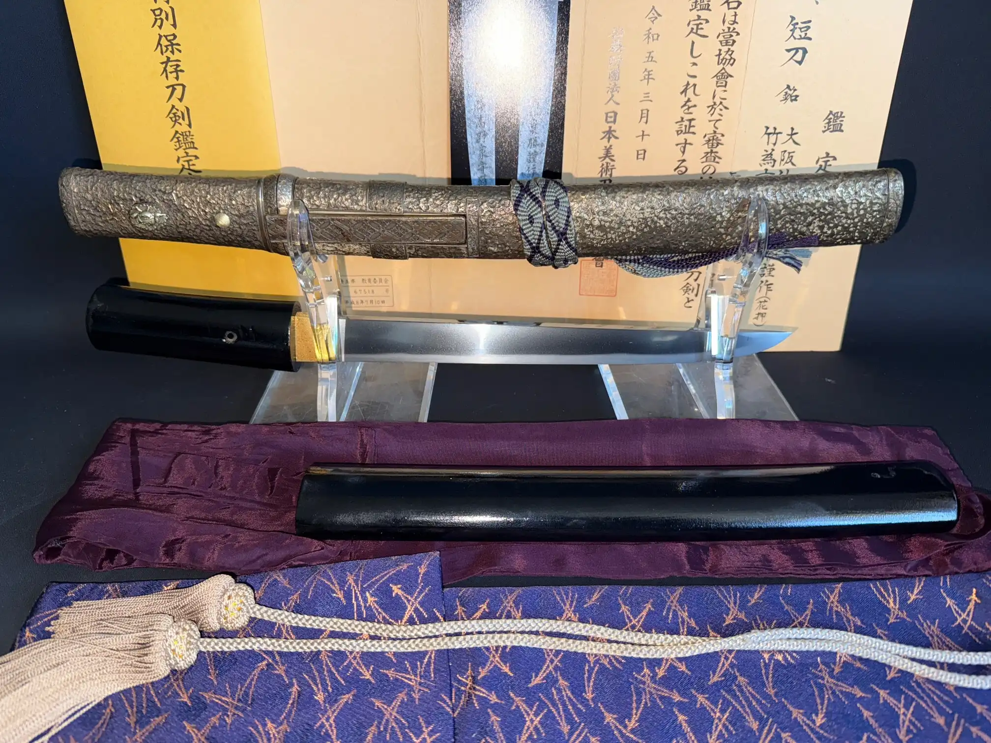 Ornate silver saya and black tsuka of Tanto Gassan Sadakatsu (Tanto) with papers, from above
