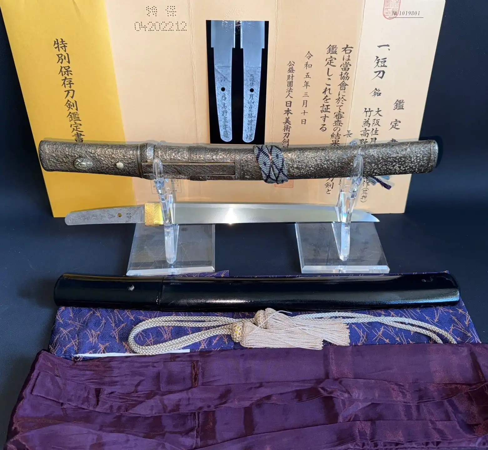 Tanto Gassan Sadakatsu, a Japanese tanto with detailed handle and polished blade displayed with scabbard and paperwork