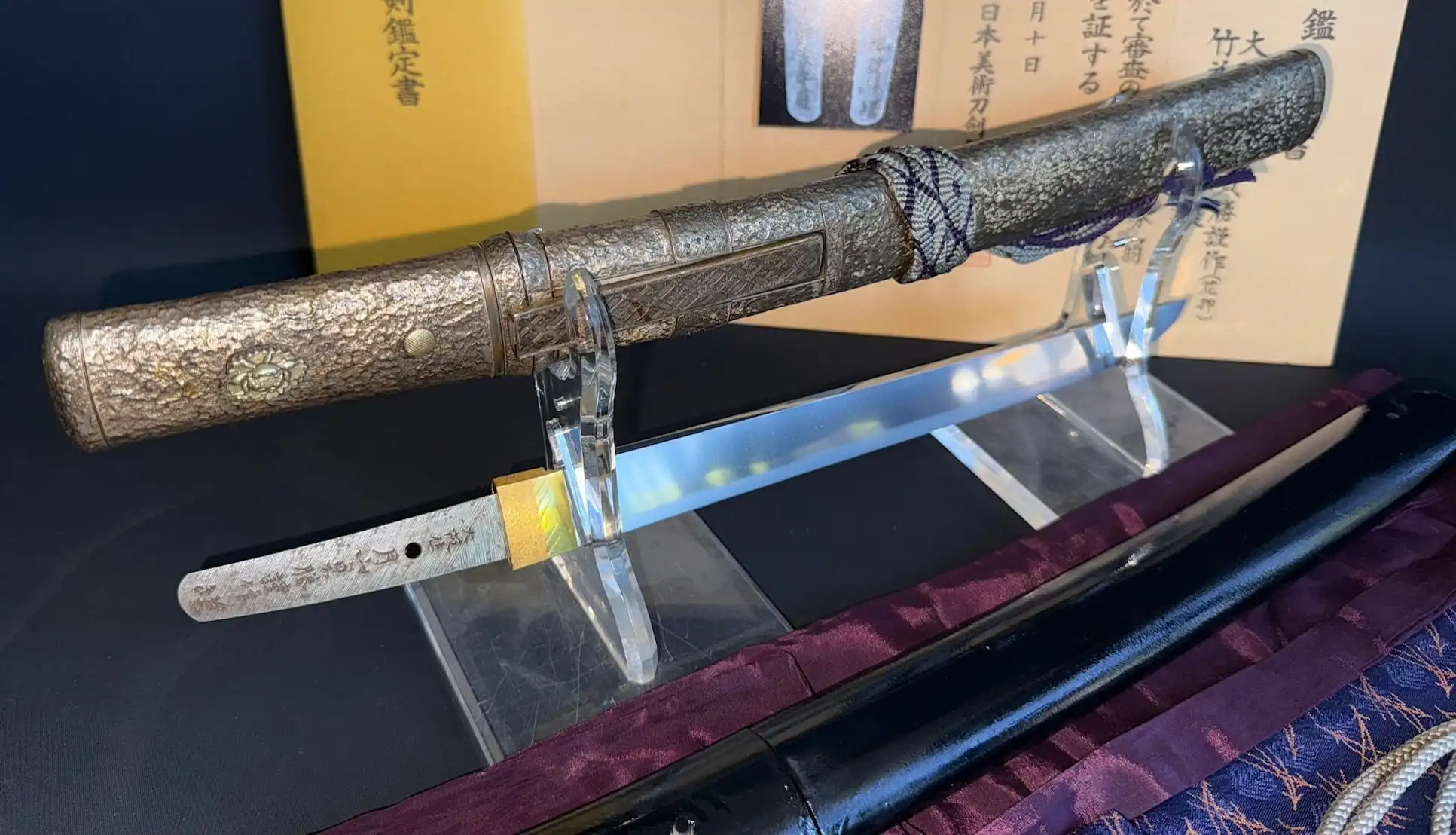Gassan Sadakatsu Tanto, partially sheathed, showing a detailed handle and sharp blade with certificate