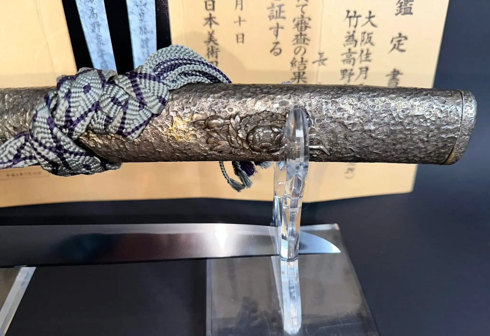 Kyodai Originals Tanto Gassan Sadakatsu, close up of the textured saya with detailed carving and a silk cord tie.