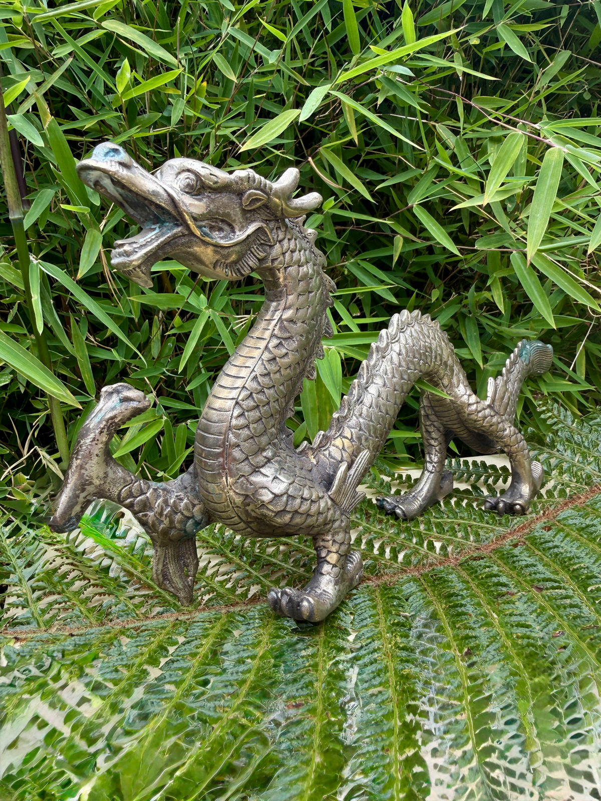Japanese Silvered Dragon Sculpture Meiji Period style, a detailed katana artifact, set against green foliage.