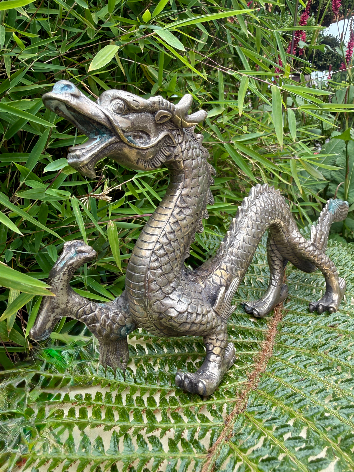 Silvered Japanese dragon sculpture (Meiji Period style) with open mouth, shown amongst green foliage, for katana collectors